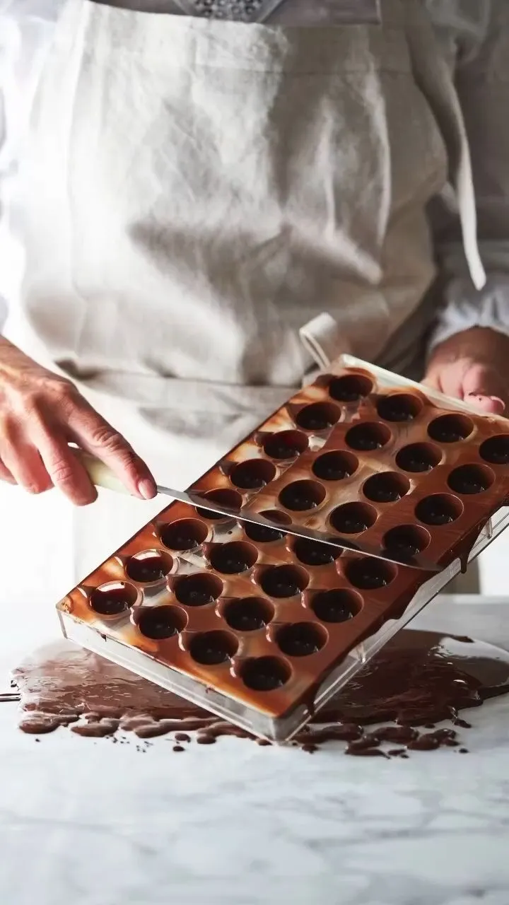 Un chocolatier démoule une plaque de bonbons au chocolat